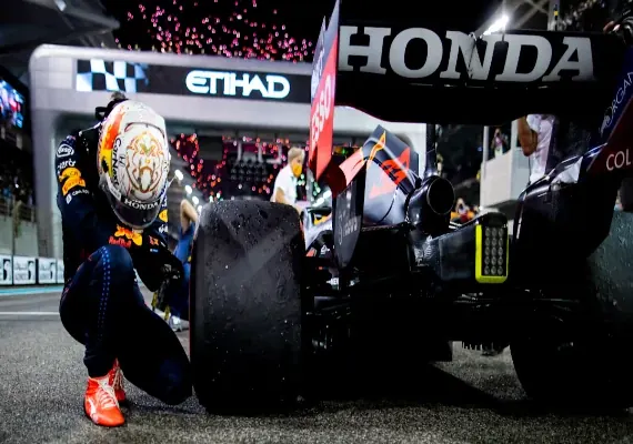 Max Verstappen kneeling beside his Red Bull car after the 2021 title decider in Abu Dhabi.