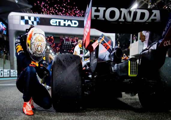 Max Verstappen kneeling beside his Red Bull car after the 2021 title decider in Abu Dhabi.
