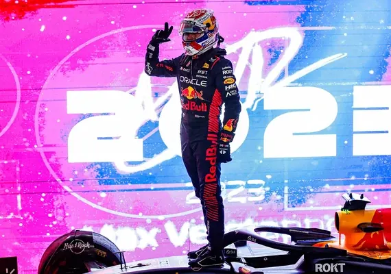 Max Verstappen celebrating atop his Red Bull car after winning the 2023 Formula 1 title.